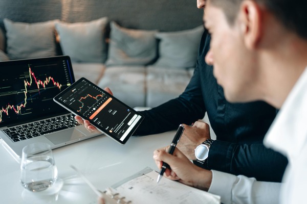 Traders reviewing cryptocurrency price charts on a laptop and tablet