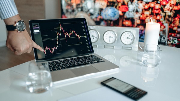 Laptop showing a cryptocurrency candlestick chart next to world clocks
