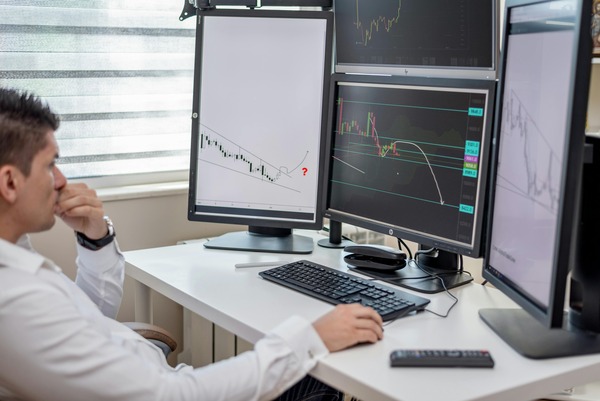 Trader analyzing multiple cryptocurrency price charts on desktop monitors