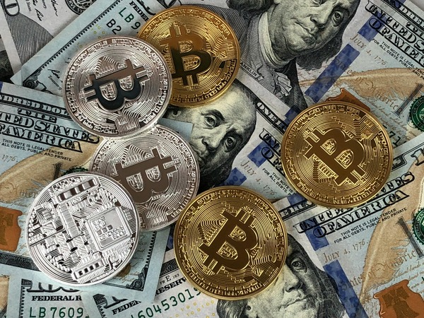 Bitcoin and silver cryptocurrency coins resting on US dollar bills