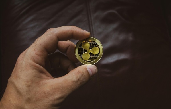 Hand holding a cryptocurrency coin to verify a wallet transaction